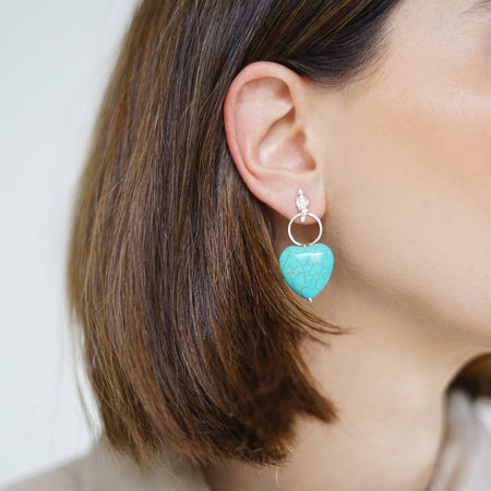 Handcrafted Turquoise Heart Drop Earrings featuring heart-shaped turquoise stones made in sterling silver.