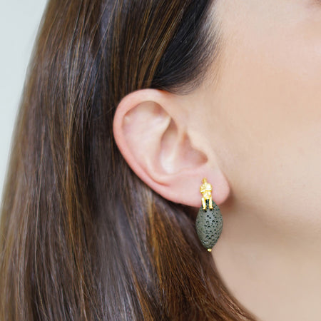 Woman wearing olive volcanic drop earrings featuring natural volcanic stones with 18K gold-plated sterling silver accents at the top.